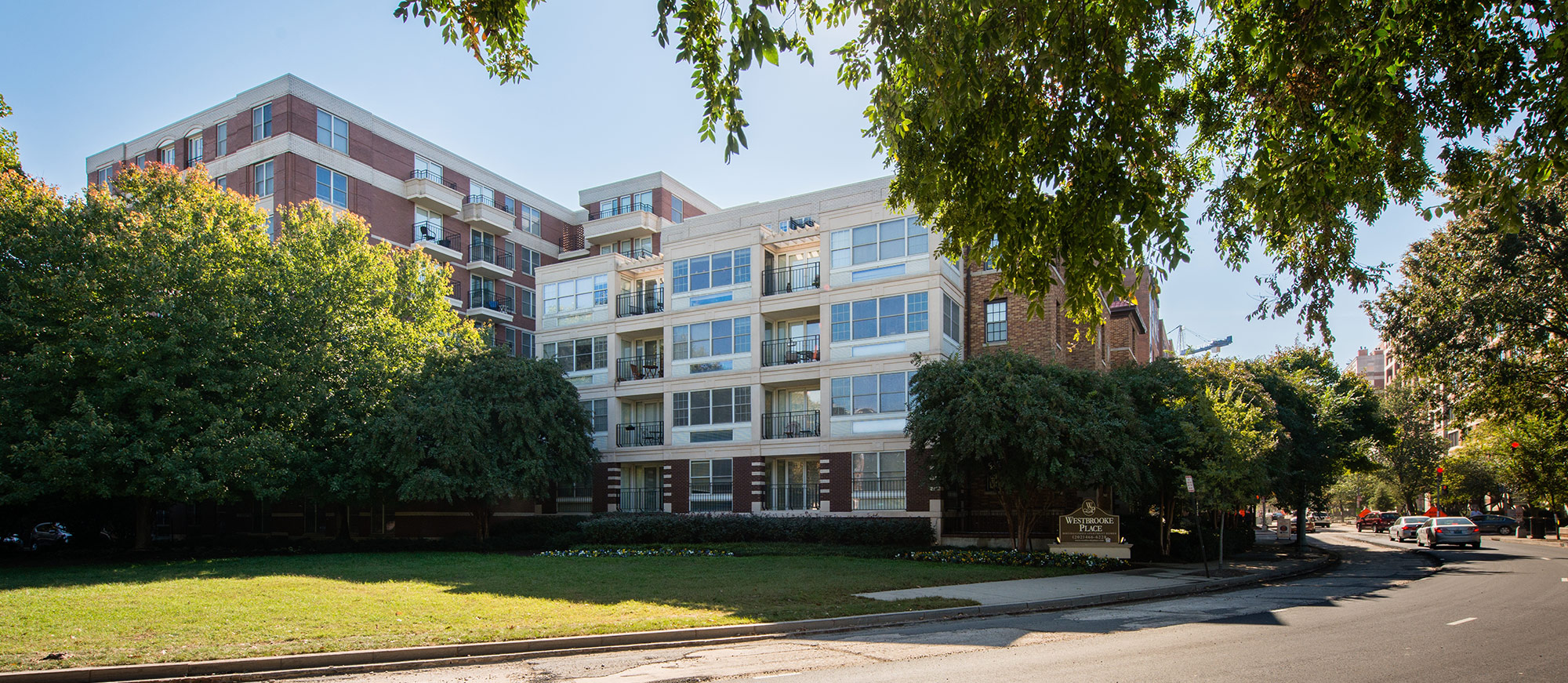Exterior street view of apartment complex with surrounding trees and green landscaping