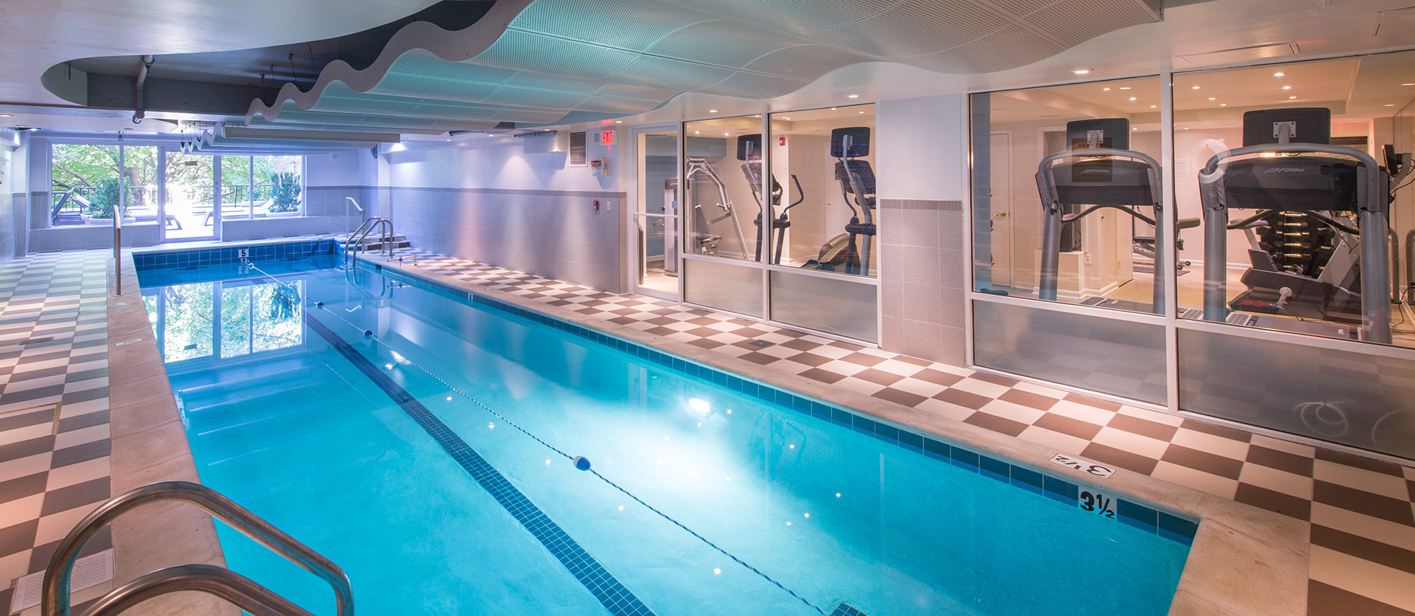Indoor swimming pool with tile flooring and access to indoor gym
